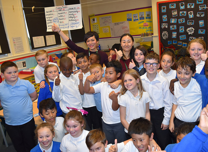 year-5-at-gorse-hill-primary-school-give-thumbs-up-for-shanghai-maths-lesson-with-teachers-jinjin-left-and-zhang-right-resized