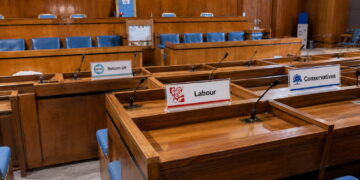 Swindon Borough Council chamber with desks displaying Reform UK, Labour and Conservative nameplates ahead of a Finance Recovery Board meeting.